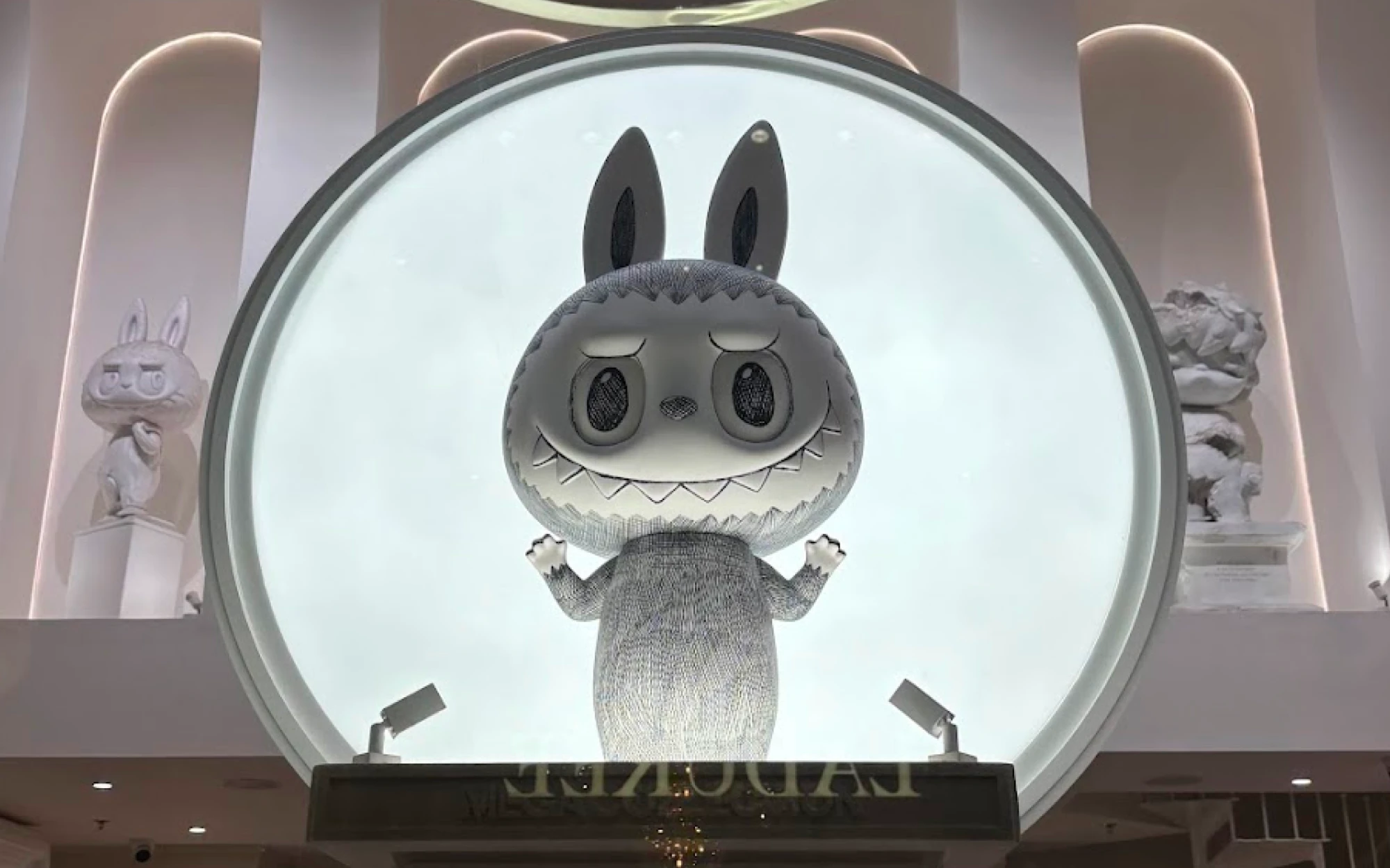 Giant black-and-white Labubu figure with pointed ears and a toothy grin, on display at the Pop Mart store in the Louvre Museum in Paris